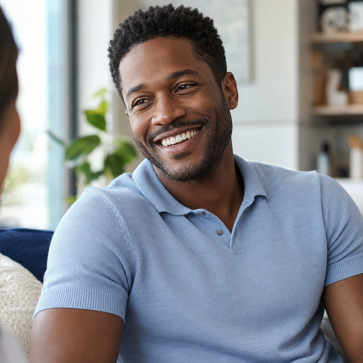 Black adult man sharing a relaxed natural smile during a conversation at home